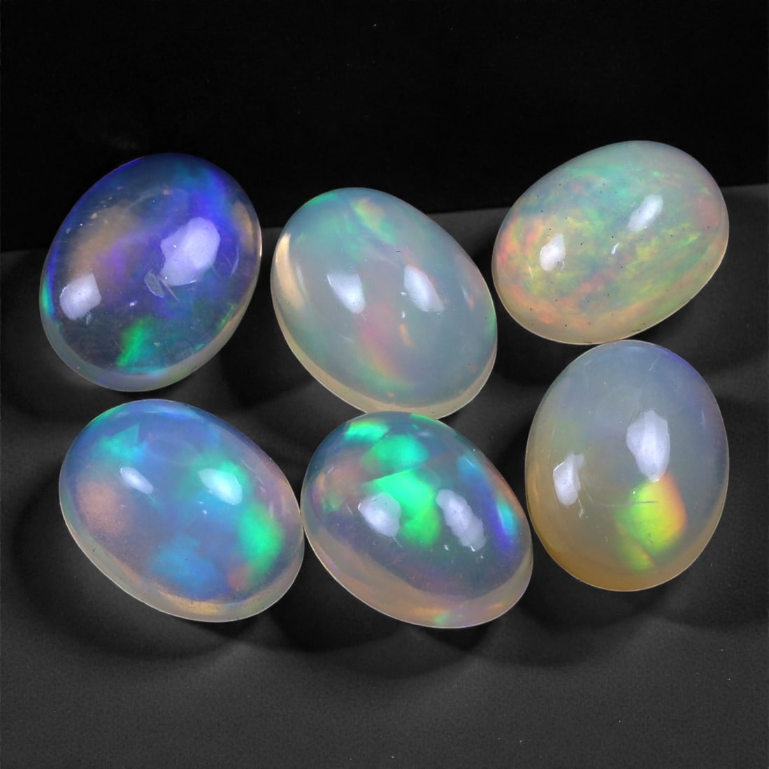 7.77 Carats Neon Play-of-Color Opal Selection - Natural Ethiopian Cabochons - 8 to 9 mm, 38XC: This luminous selection of opals radiates a dynamic spectrum of neon hues, with flashes of electric green, vivid orange, and spectral blue dancing across each dome. Their translucent base allows the i