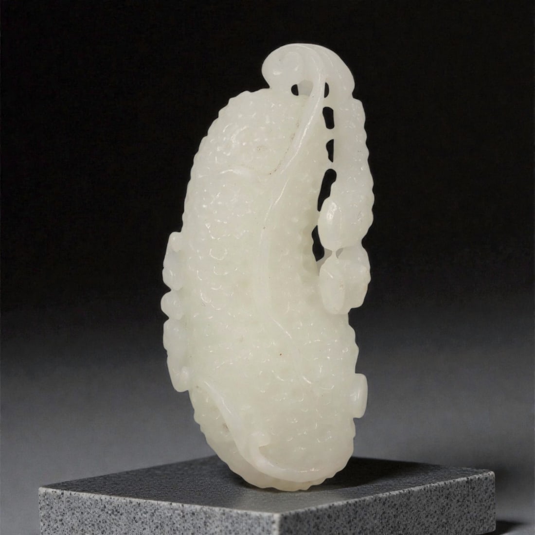 A Chinese Nephrite Jade Melon-Form Pendant, 20th Century, 47FB: Carved from pale white Hetian nephrite with soft translucency and minor natural inclusions, the pendant is modeled in the form of an elongated melon. The body is subtly lobed, with gently rounded cont