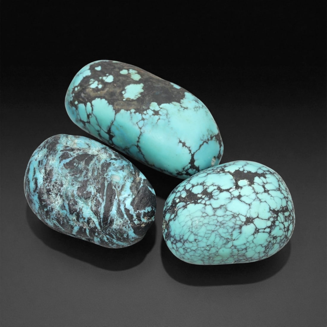 A Group of Three Tibetan Turquoise Beads, 20th Century, 9EX: A set of three substantial, barrel-shaped Tibetan turquoise beads, each exhibiting the characteristic vibrant sky-blue hue and natural matrix inclusions of authentic Himalayan turquoise. The beads var