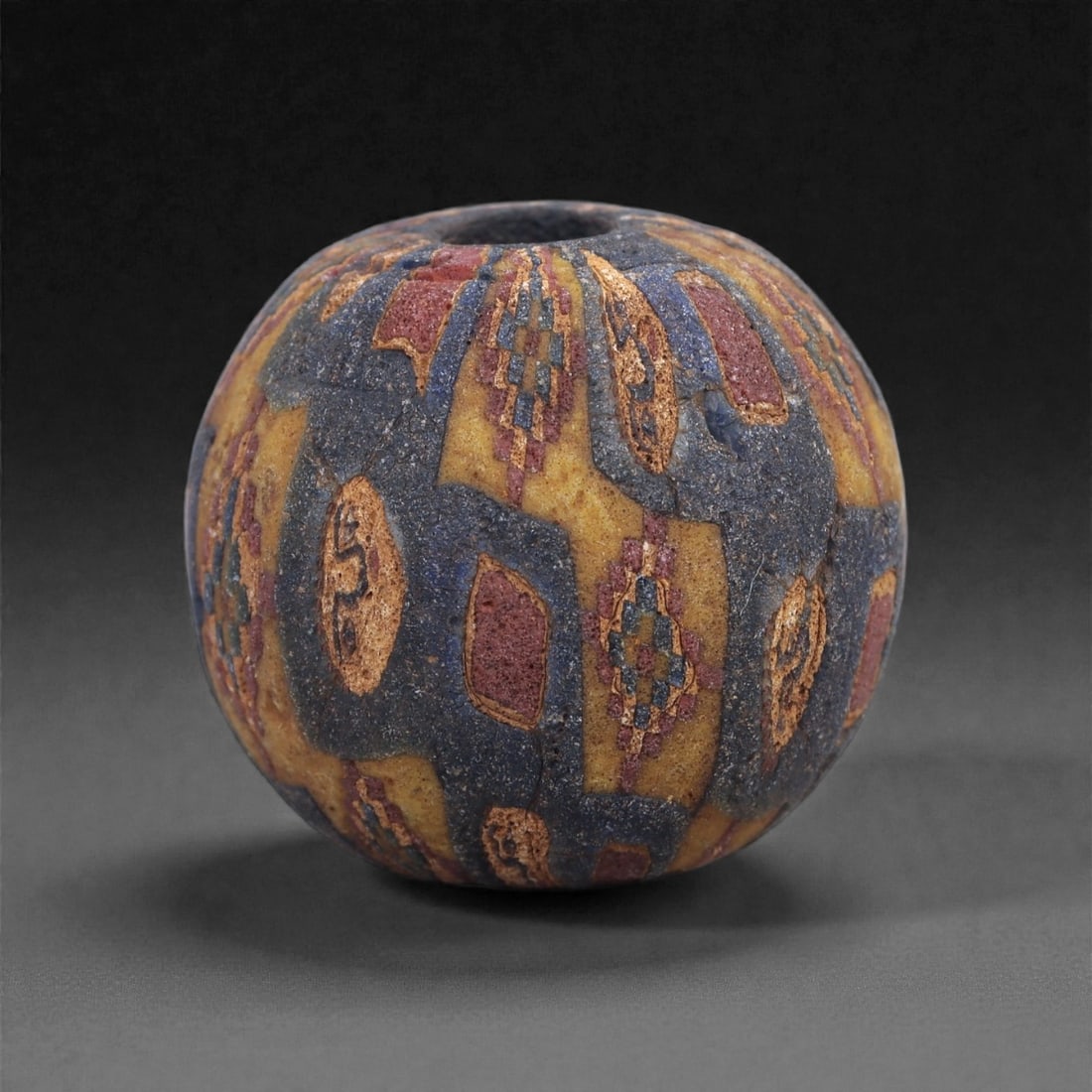Ancient Glass Bead - Egypto-Roman Mosaic Cane Sphere, 29J: Composed of multicolored mosaic canes arranged in alternating vertical panels, this bead reflects the glassworking traditions of the Egypto-Roman world during the early centuries CE. The intricate tes