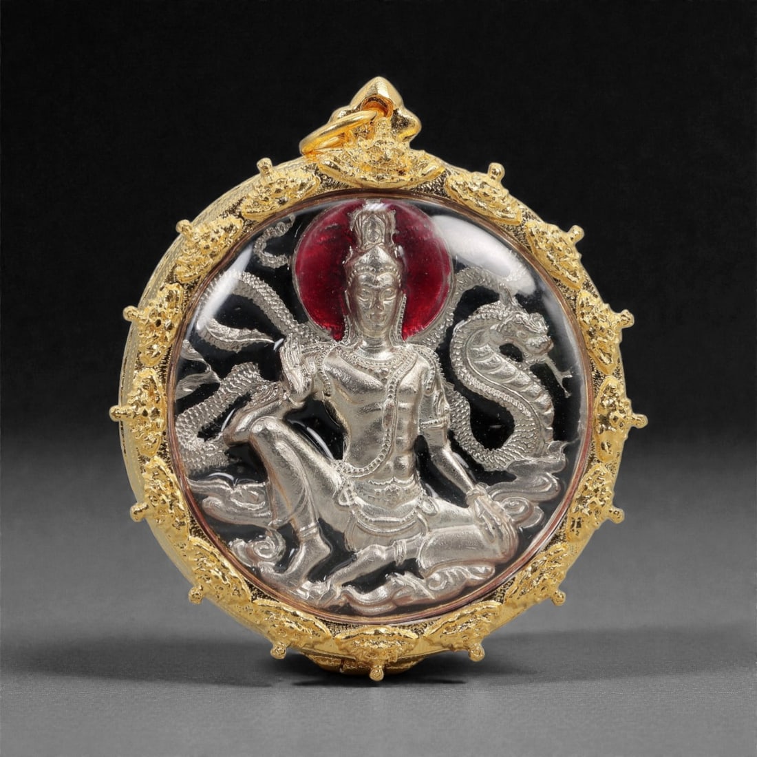 A Thai Buddhist Bimetallic Amulet in Gilt Metal Frame, 20th Century, 58FN: The amulet is set within a circular gilt metal frame featuring filigree and repousse decorative borders, with a suspension loop at the apex. The obverse displays a silvered metal high-relief figure of