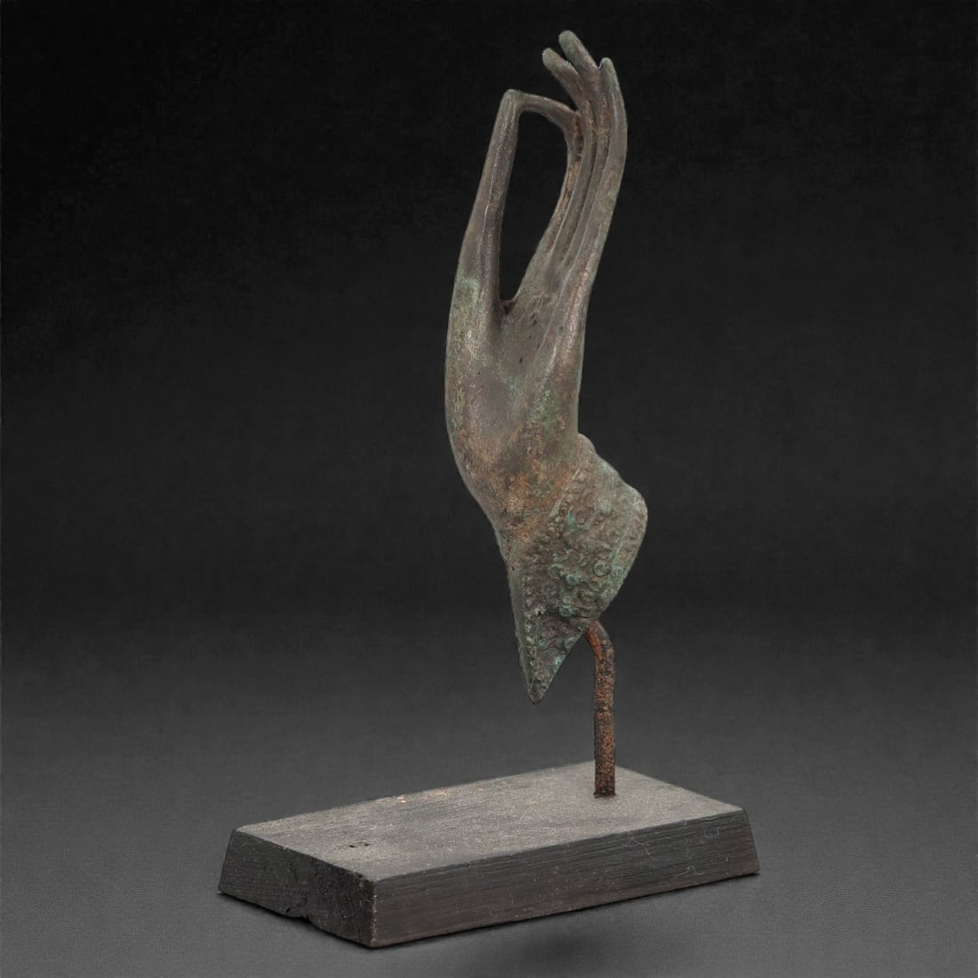 A Southeast Asian Bronze Buddha Hand, 20th Century, 33FN: Cast from bronze with a dark, aged patina and scattered greenish verdigris encrustation, the hand is rendered in a stylized, elongated form with the thumb and index finger forming a circular gesture,