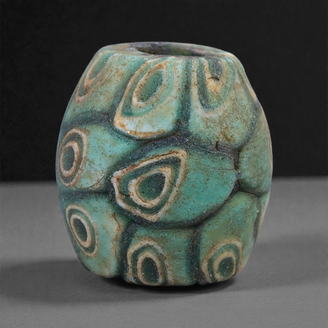 Antique Glass Bead - Venetian Molded Eye-Motif Cylinder, 40J: Worked in layered turquoise, cream, and deep green glass, this bead displays the molded eye motifs characteristic of Venetian production from the late medieval to early modern period. The raised, shie