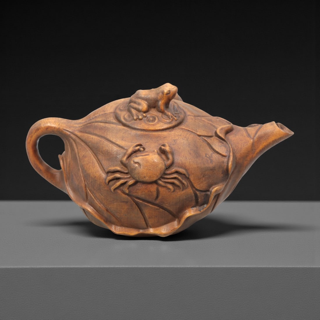 A Chinese Wood Teapot Sculpture, 20th Century, 63FH: Carved from a single block of hardwood with a warm brown tone and visible natural grain, the object is modeled in the form of a teapot with an integrated lid, spout, and handle. The body is formed as