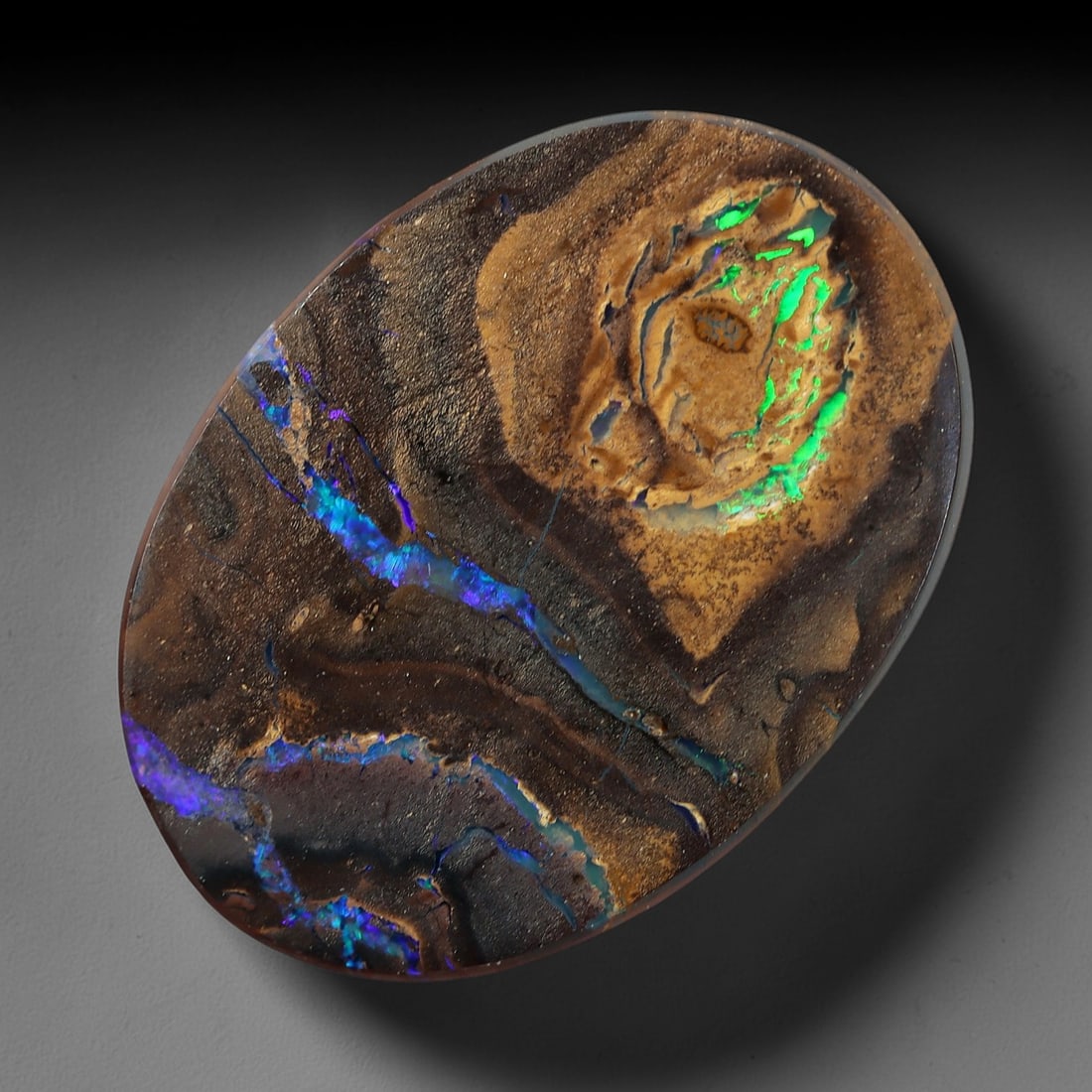 3.44 Carats Koroit Boulder Opal Cabochon - Natural Australian Stones 14.7x10.5mm, 16XM: This exceptional 3.44-carat Koroit boulder opal cabochon is a natural work of geological art, featuring vivid veins of electric blue, deep violet, and luminous green play-of-color that snake through a