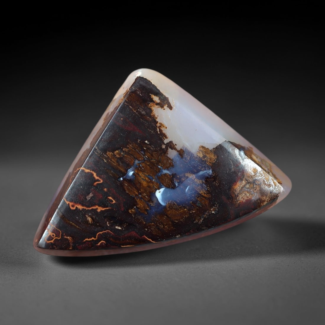 7.27 Carats Soft Blue and Lavender Boulder Opal Cabochon - Natural Australian Stone, 63XM: This substantial boulder opal cabochon features a soft, milky base of pale blue and lavender, infused with delicate, iridescent undertones that shift with light. The stone's triangular form showcases