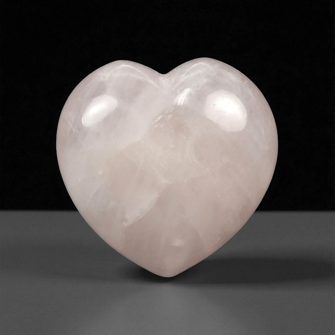 95.26 Carats Soft Pink Rose Quartz Heart - Natural Madagascar Carving, 51XC: This elegantly carved rose quartz heart glows with a gentle blush pink hue, showcasing the serene, milky translucence that defines fine-quality rose quartz. Subtle internal veils and delicate marbling