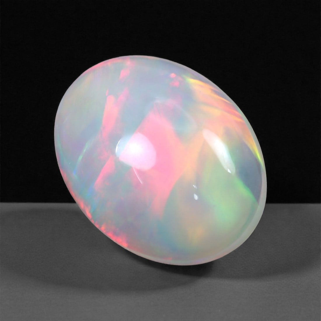 3.67 Carats Sunset Bloom Welo Opal - Natural Ethiopian Gemstone 13.5x10.5x5.6mm, 27XH: This captivating Welo opal bursts with vibrant waves of rose pink, neon green, and golden fire, all swirling beneath a luminous translucent surface. The internal color display is broad and painterly, 