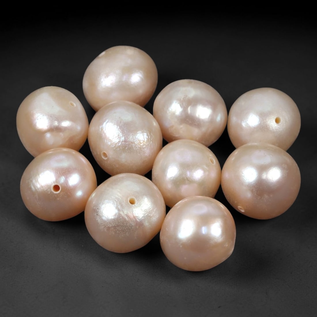 A Group of Ten Baroque Cultured Pearls, 100ZH: Comprising ten baroque cultured pearls, each of spherical to slightly irregular form with a soft pinkish-white hue and delicate iridescent overtones. Each pearl features a small, precisely drilled hol