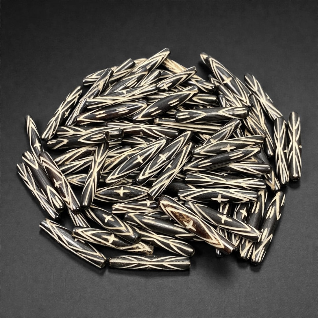A Lot of Tibetan Bone Beads, 20th Century, 69S: A large grouping of tubular bone beads, characteristic of Tibetan Buddhist prayer bead components. Each bead is uniformly shaped with a long, slender form and features the iconic contrast of deeply in