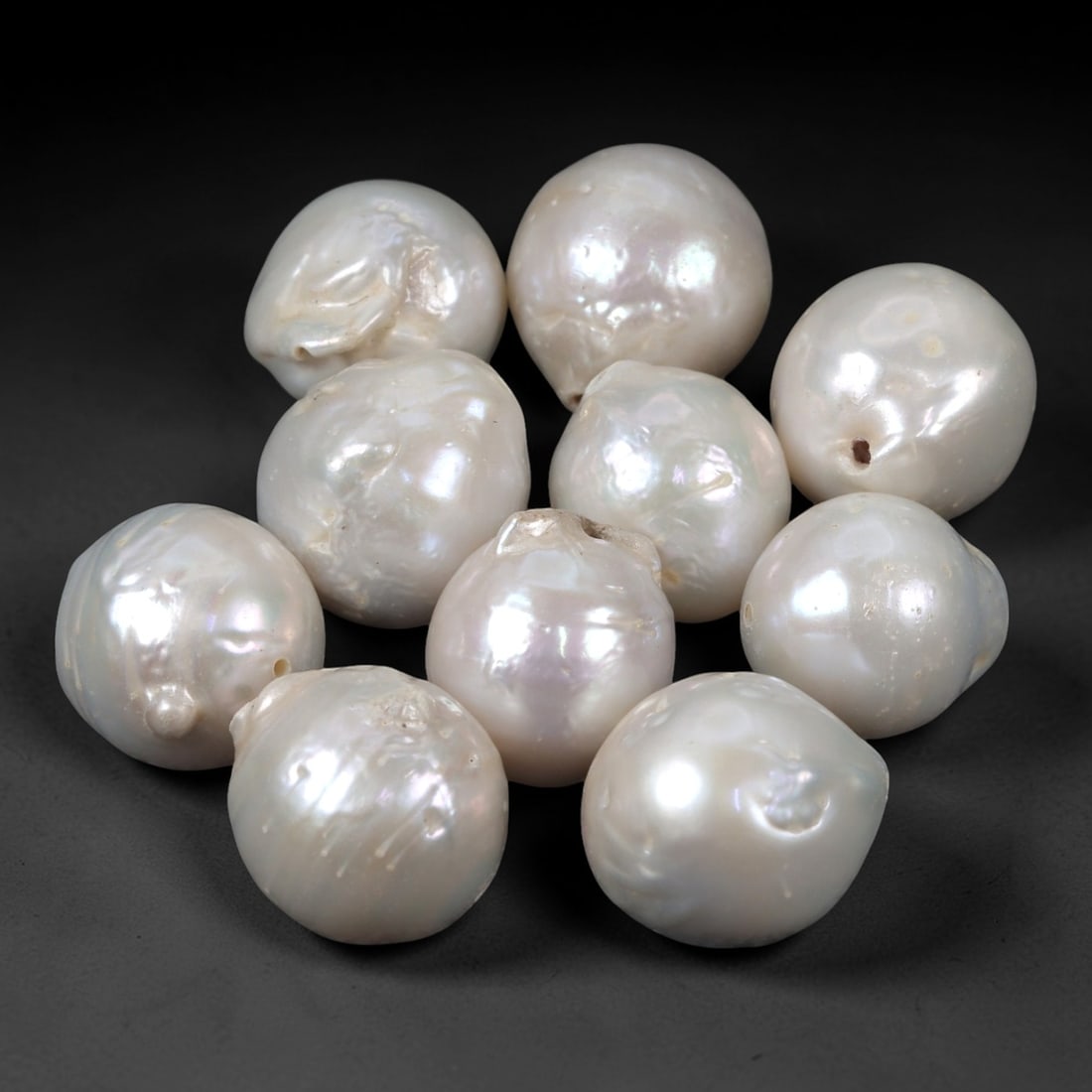 A Group of Ten Baroque Cultured Pearls, 95ZH: Comprising ten baroque cultured pearls, each with a natural, irregular shape and lustrous white to pale iridescent surface. The pearls exhibit subtle variations in form, with some featuring minor surf