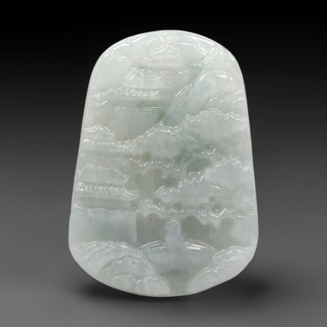 A Chinese Jade Landscape Pendant, 20th Century, 89XL: Carved from pale greenish-white jade with subtle natural inclusions, the pendant is shaped in an irregular, slightly tapering form with a suspension hole at the top. The front surface is carved in low