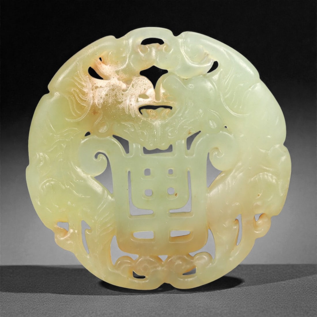 A Chinese Hetian Jade Openwork Longevity Plaque, 20th Century, 65FH: Carved from pale celadon Hetian nephrite jade with areas of natural russet and honey-colored inclusions, the plaque is circular in form and worked in openwork relief. The central field is pierced and