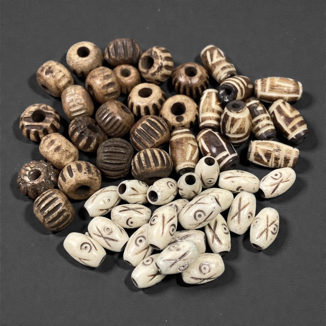 A Tibetan Bone Bead Group, Incised Geometric and Zoomorphic Pattern, 20th Century, 66S: Composed of animal bone, the group consists of beads of varied forms, including flattened spherical and barrel-shaped types, all with central axial perforations for stringing. The surface displays inc