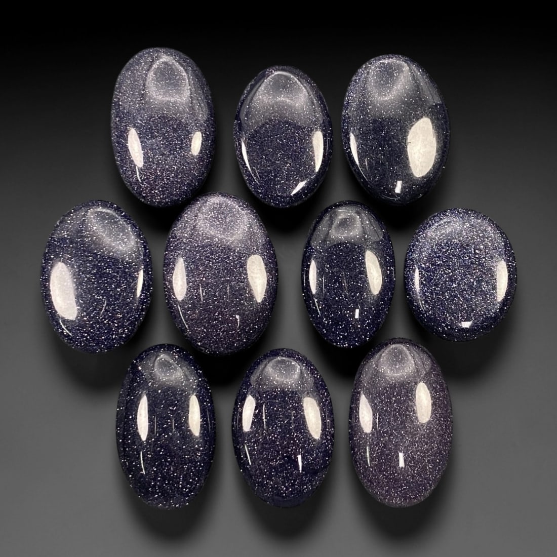 224.49 Carats Midnight Blue Goldstone Oval Cabochon Parcel 2.3-2.8cm, 75ZJ: This substantial parcel of midnight blue goldstone oval cabochons shimmers with a celestial, star-like sparkle that captures the imagination. Set against a deep, velvety indigo base, each stone is den