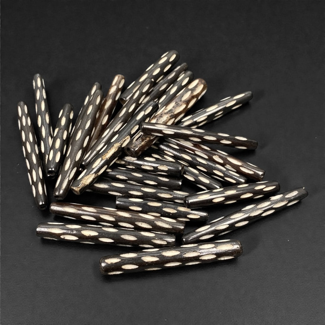 A Tibetan Bone Bead Group, Inlaid Polka Dot Pattern, 20th Century, 93S: Composed of animal bone, each bead features a cylindrical form with consistent length and diameter across the group. The surface displays an inlaid polka dot pattern, with regularly spaced white inlai