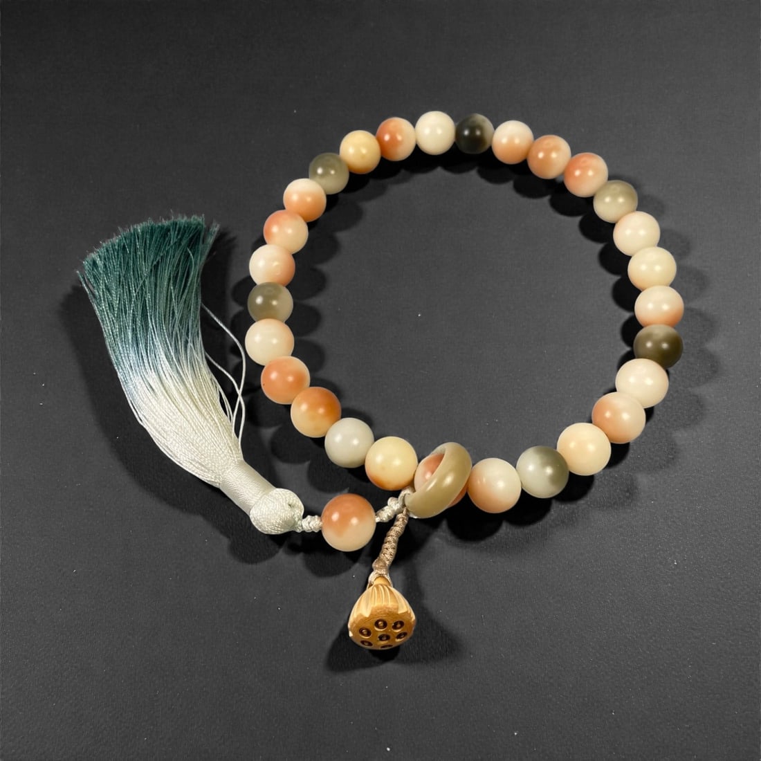 A Chinese Hardstone Prayer Bead Bracelet, 20th Century, 100FD: Composed of spherical beads carved from multicolored hardstone with tones ranging from pale cream and soft peach to muted green, each bead evenly shaped and smoothly polished. The beads are strung to 