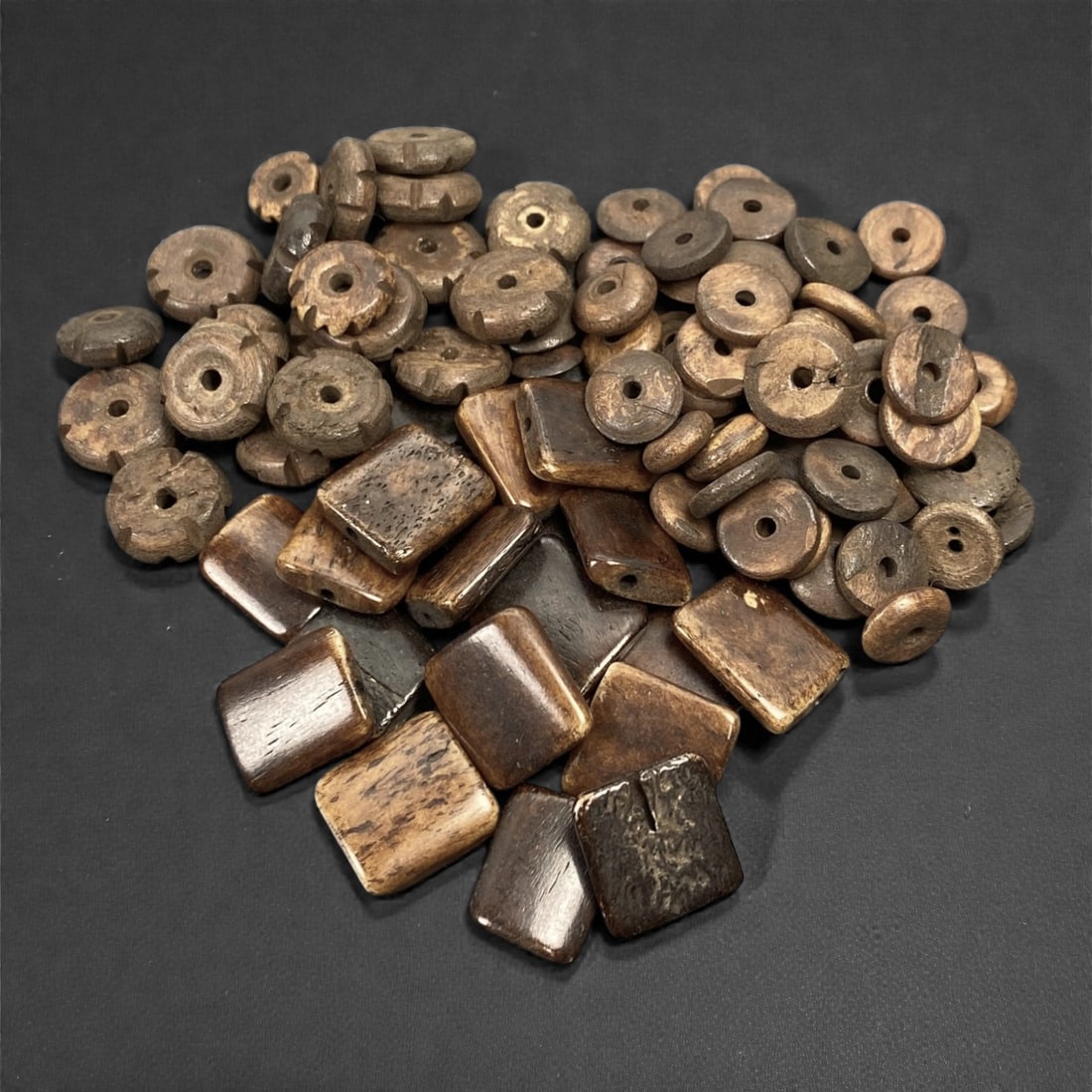 A Tibetan Bone Bead Group, Plain and Incised Form, 20th Century, 74S: Composed of animal bone, the group consists of beads of varied forms, including circular disc-shaped and square-shaped types, all with central axial perforations for stringing. Some beads display inci