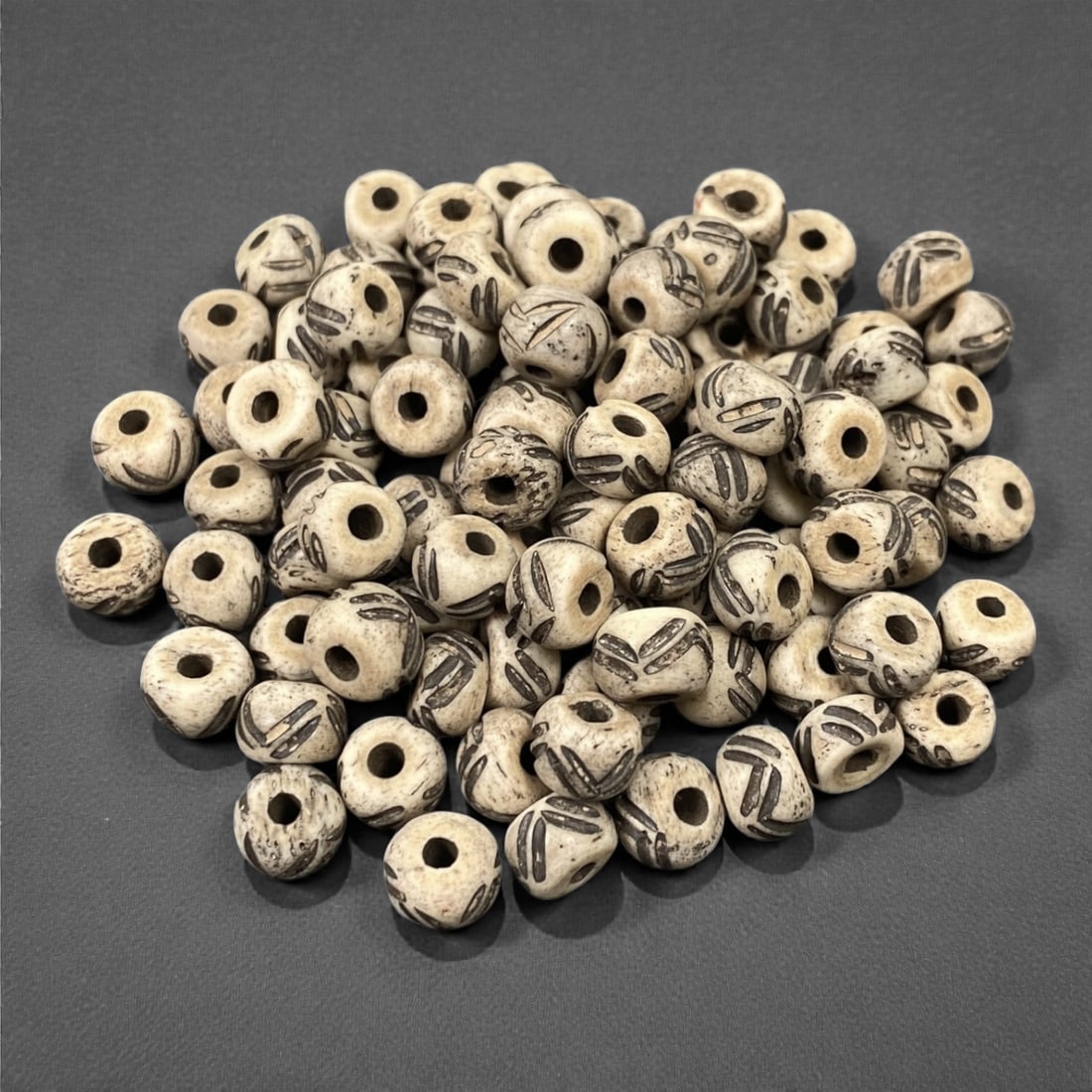A Tibetan Bone Bead Group, Incised Linear Pattern, 20th Century, 85S: Composed of animal bone, each bead features a flattened spherical form with a central axial perforation for stringing. The surface displays incised linear motifs, with dark pigment filling the grooves