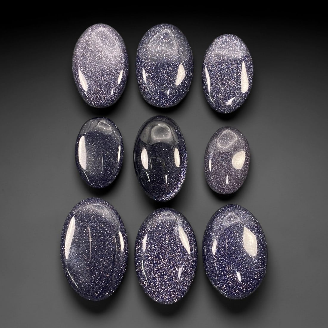 116.66 Carats Midnight Blue Goldstone Oval Cabochon Parcel 1.8-2.7cm, 76ZJ: This curated parcel of midnight blue goldstone oval cabochons shimmers with a celestial, star-like sparkle that captures the imagination. Set against a deep, velvety indigo base, each stone is densely