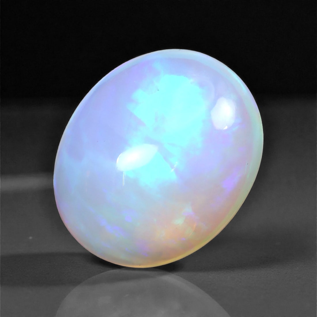 3.37 Carats Ice Blue Flash Welo Opal - Natural Ethiopian Gemstone 12.5x10.1x6mm, 15XH: This radiant Welo opal features a crisp, icy-blue flash layered with subtle lavender and warm peach undertones. The gem's translucent body allows light to pass through effortlessly, creating an ethere
