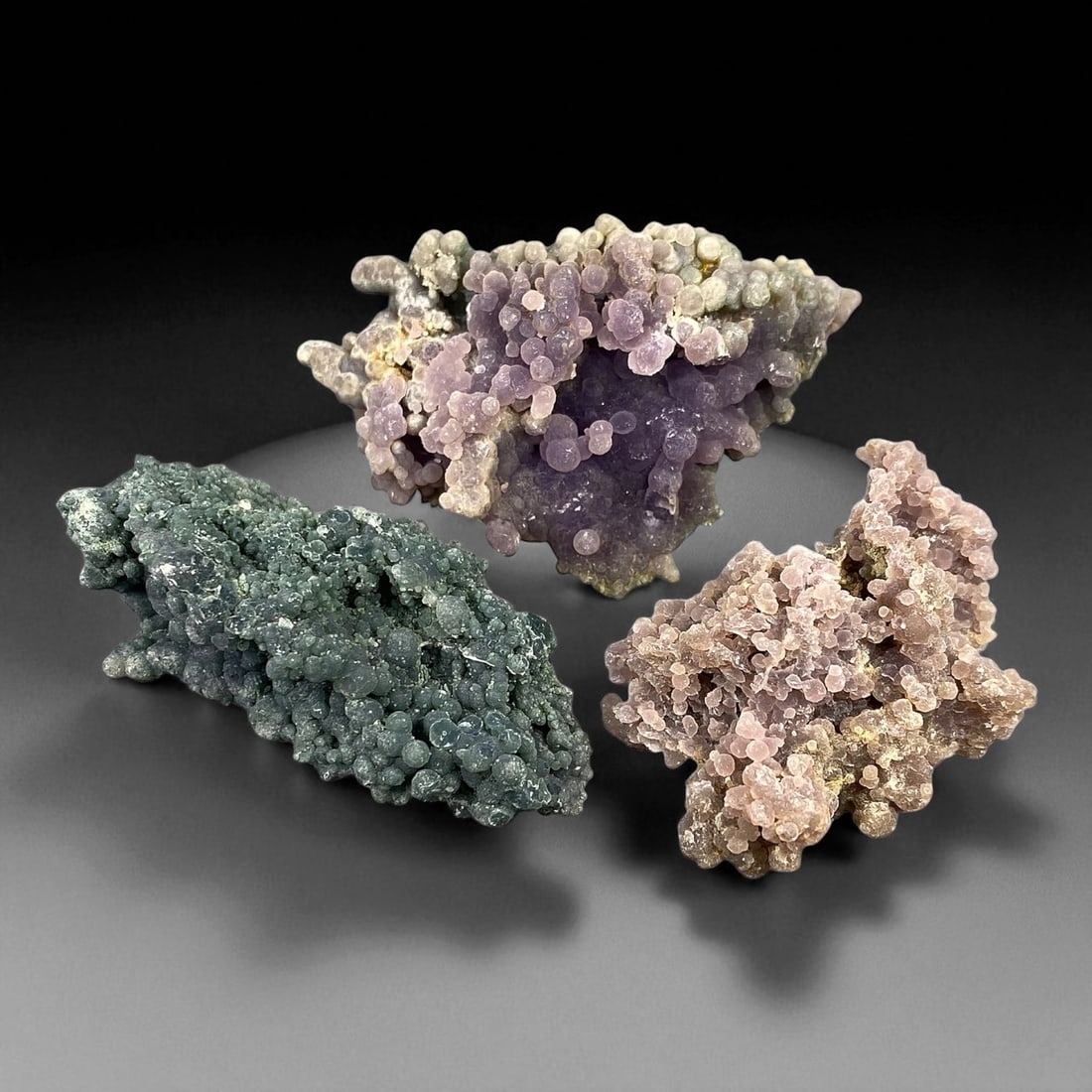 A Group of Three Grape Agate Specimens, 55EC: A group of three grape agate specimens, ranging in size from 5.7 to 6.7 cm. The specimens exhibit characteristic botryoidal formations, with individual spherical aggregates resembling clusters of grap