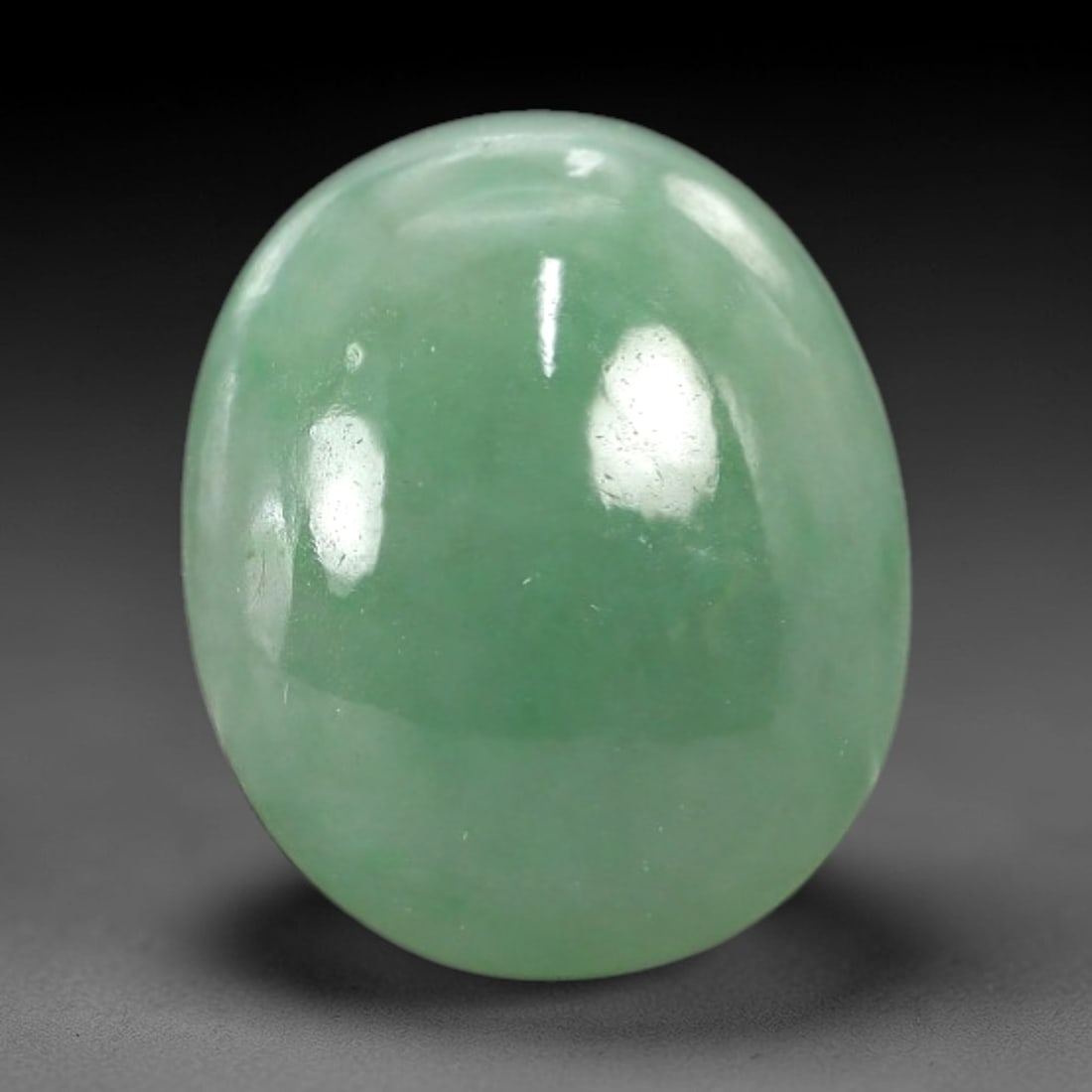 4.65 Carats Apple Green Jadeite Cabochon - Natural Burmese Stone, 77AB: This oval jadeite cabochon features a consistent apple green hue with a refined, semi-translucent body that captures light with a muted, even luminescence. The precision domed cabochon cut optimizes t