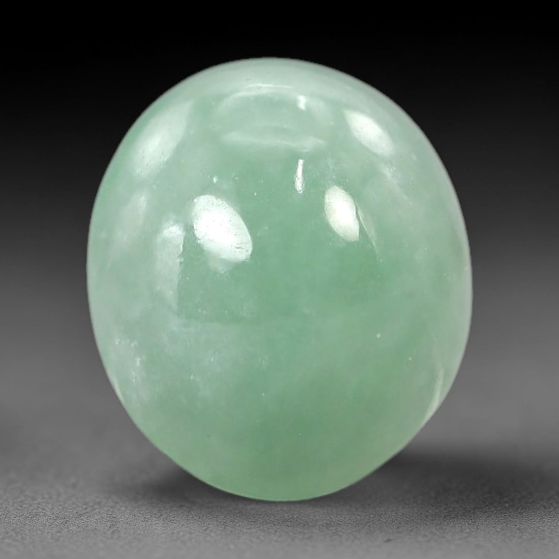 4.74 Carats Apple Green Jadeite Cabochon - Natural Burmese Stone, 67AB: This oval jadeite cabochon features a consistent apple green hue with a refined, semi-translucent body that captures light with a muted, even luminescence. The precision domed cabochon cut optimizes t