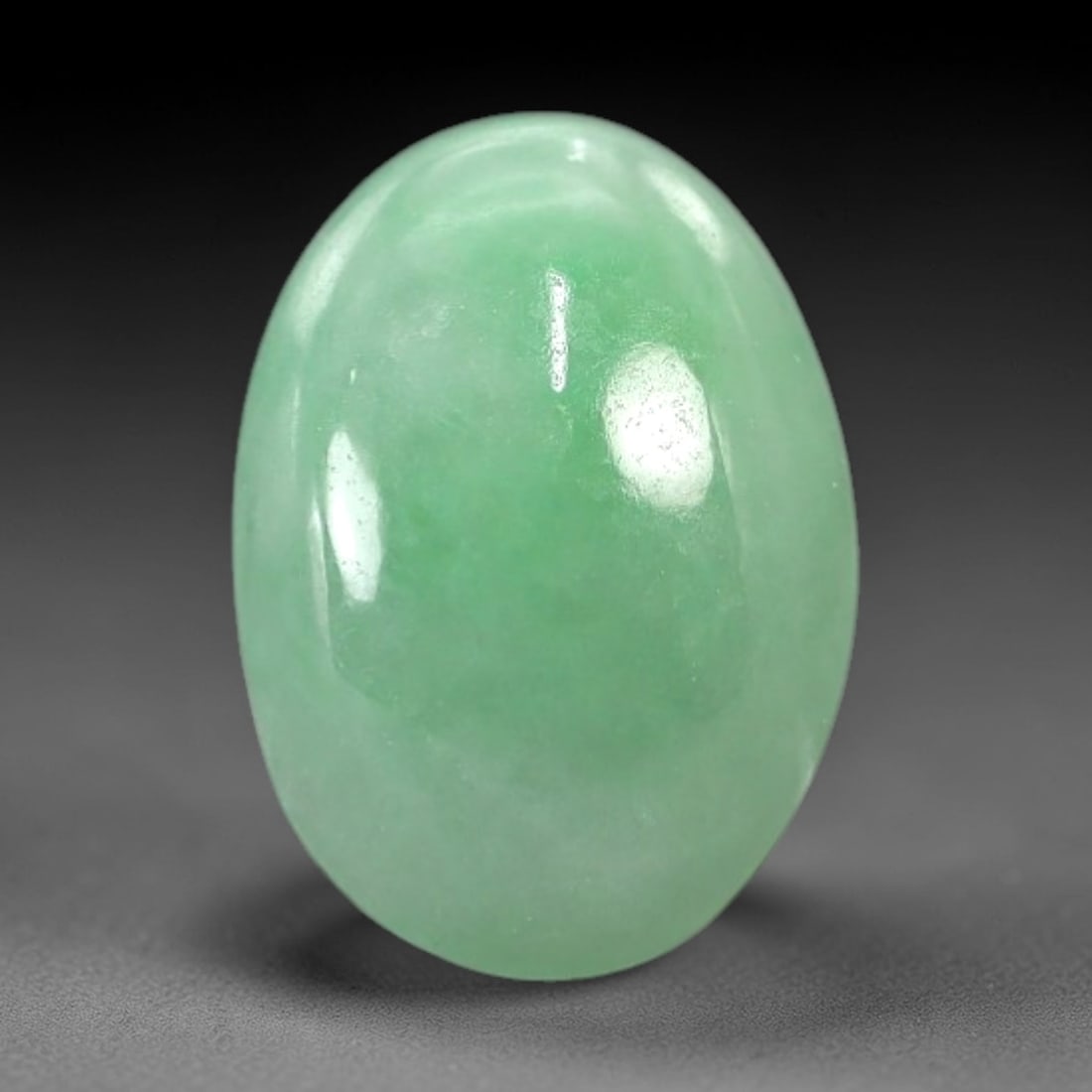 3.69 Carats Apple Green Jadeite Cabochon - Natural Burmese Stone, 76AB: This oval jadeite cabochon features a uniform apple green hue with a refined, semi-translucent body that captures light with a muted, even luminescence. The precision domed cabochon cut optimizes the
