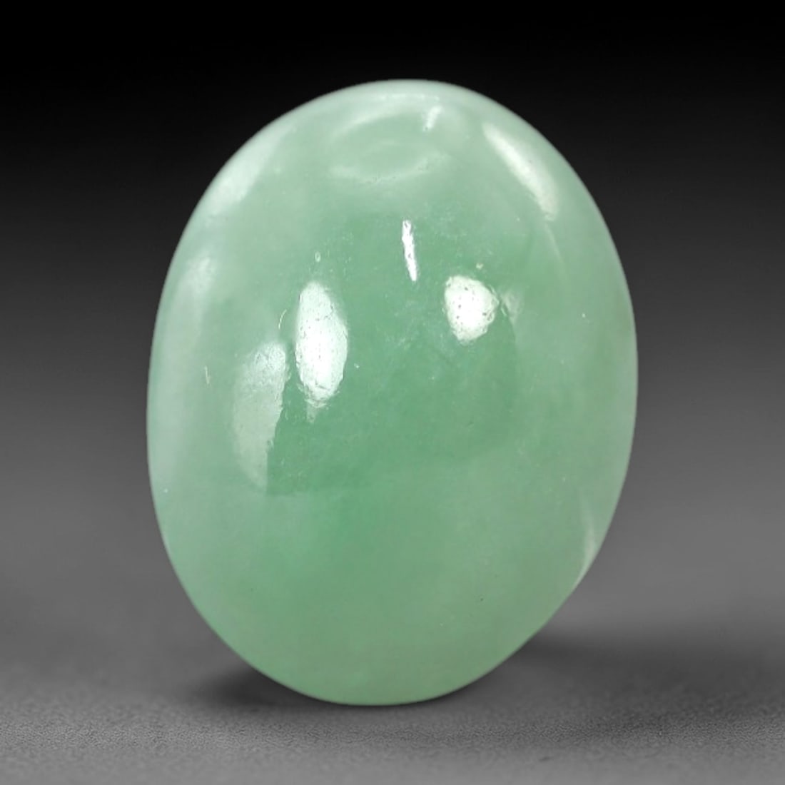 6.38 Carats Apple Green Jadeite Cabochon - Natural Burmese Stone, 90AB: This oval jadeite cabochon features a uniform apple green hue with a refined, semi-translucent body that captures light with a muted, even luminescence. The precision domed cabochon cut optimizes the