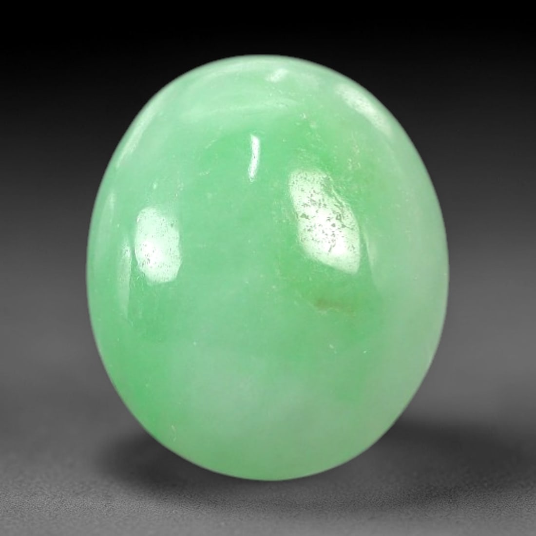 4.52 Carats Apple Green Jadeite Cabochon - Natural Burmese Stone, 89AB: This oval jadeite cabochon features a uniform apple green hue with a refined, semi-translucent body that captures light with a muted, even luminescence. The precision domed cabochon cut optimizes the
