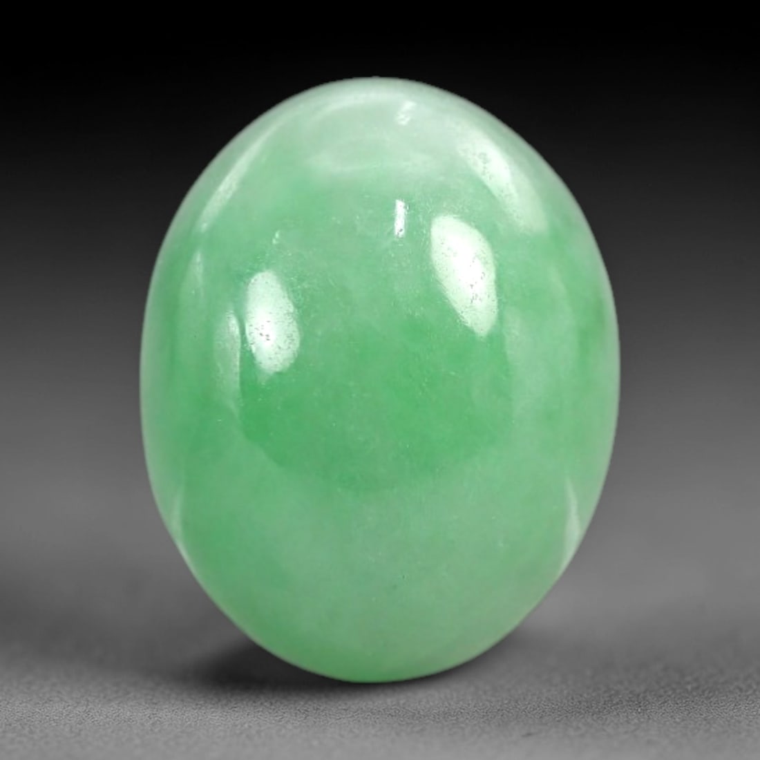 4.78 Carats Apple Green Jadeite Cabochon - Natural Burmese Stone, 93AB: This oval jadeite cabochon features a uniform apple green hue with a refined, semi-translucent body that captures light with a muted, even luminescence. The precision domed cabochon cut optimizes the