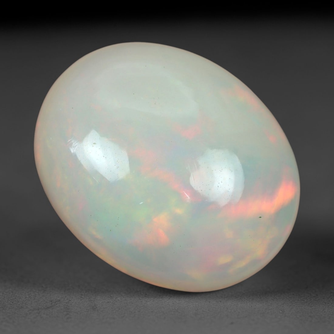 5.15 Carats Multicolor Iridescent Welo Opal Cabochon - Natural Ethiopian 14x12mm, 71XM: This luminous Welo opal cabochon radiates with a soft, milky translucence, its pale, creamy base alive with a delicate play of color. Subtle flashes of peachy-pink, golden yellow, and cool green shift