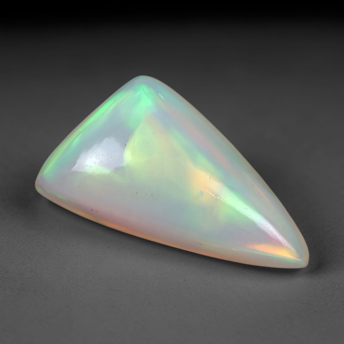 6.38 Carats Multicolor Iridescent Welo Opal Cabochon - Natural Ethiopian 17x10mm, 72XM: This luminous Welo opal cabochon radiates with a soft, milky translucence, its pale, creamy base alive with a vivid play of color. Bold flashes of peachy-pink, vibrant green, and golden yellow shift a
