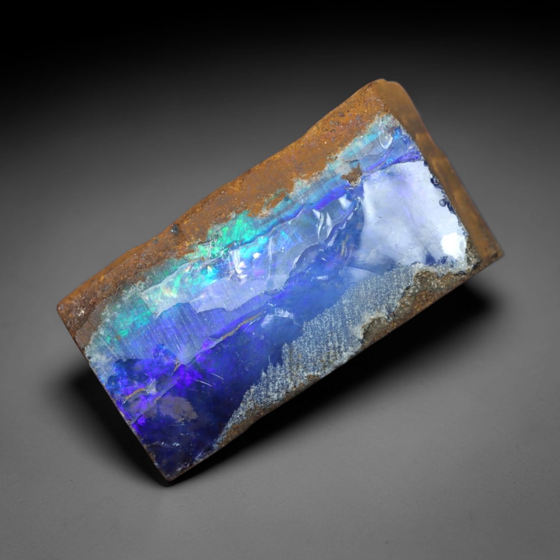 22.09 Carats Iridescent Blue-Purple Winton Opal Rough - Natural Australian Specimen 21x10mm, 85XM: This exceptional rough opal from Winton, Australia, captivates with a vivid play of color, where intense flashes of deep blue, regal purple, and vibrant green swirl through a milky, translucent base.