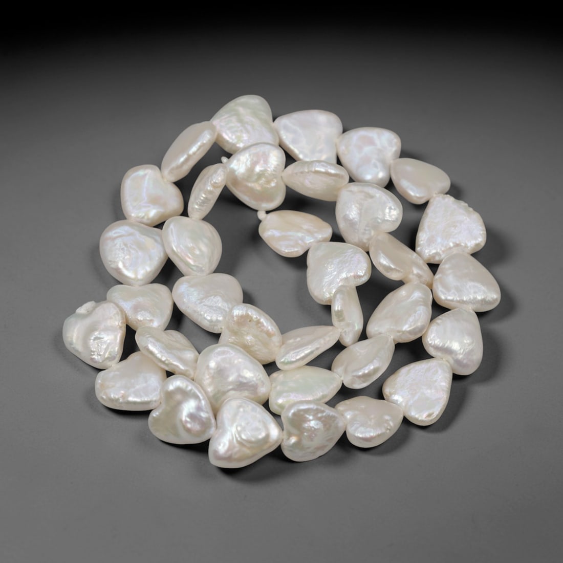 A Strand of Baroque Cultured Pearls, 20th Century, 88ZJ: Composed of baroque cultured pearls with a creamy white body color and soft iridescent overtones, the strand is strung in a single continuous line. Each pearl exhibits a highly irregular, flattened, a