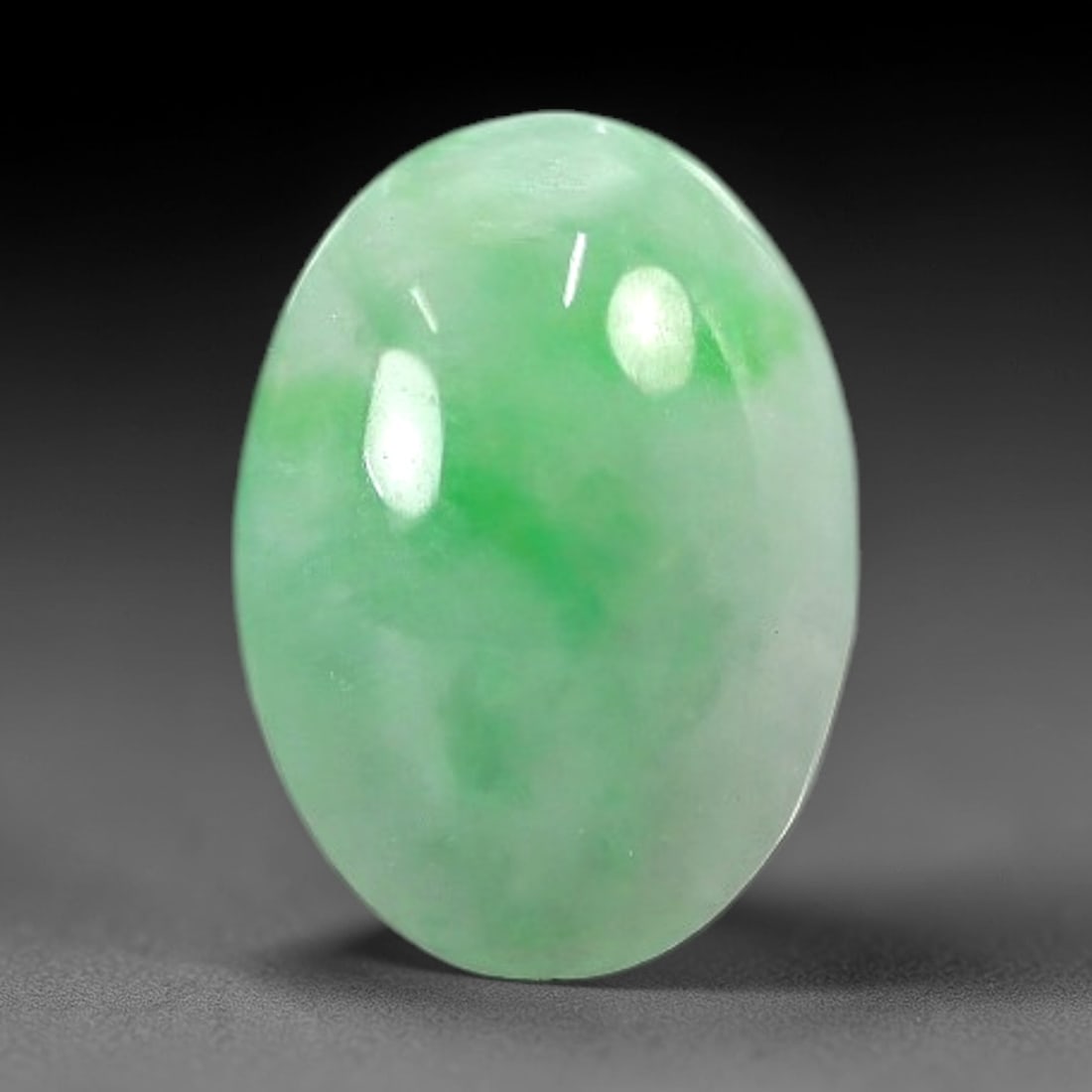 2.04 Carats Apple Green Burmese Jadeite Jade Cabochon - Natural Loose Gemstone, 51AC: This oval Burmese jadeite jade cabochon exhibits a soft apple green hue, with delicate, concentrated patches of richer green that add depth to its milky translucency. The smooth, domed cabochon cut en
