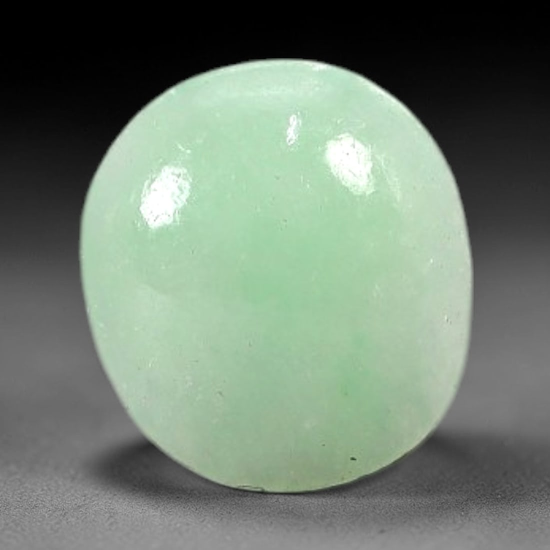 1.02 Carats Soft Mint Green Burmese Jadeite Jade Cabochon - Natural Loose Gemstone, 65AC: This oval Burmese jadeite jade cabochon exhibits a soft, uniform mint green hue, with a milky translucency that diffuses light evenly across its smooth, polished surface. The stone's even color distri