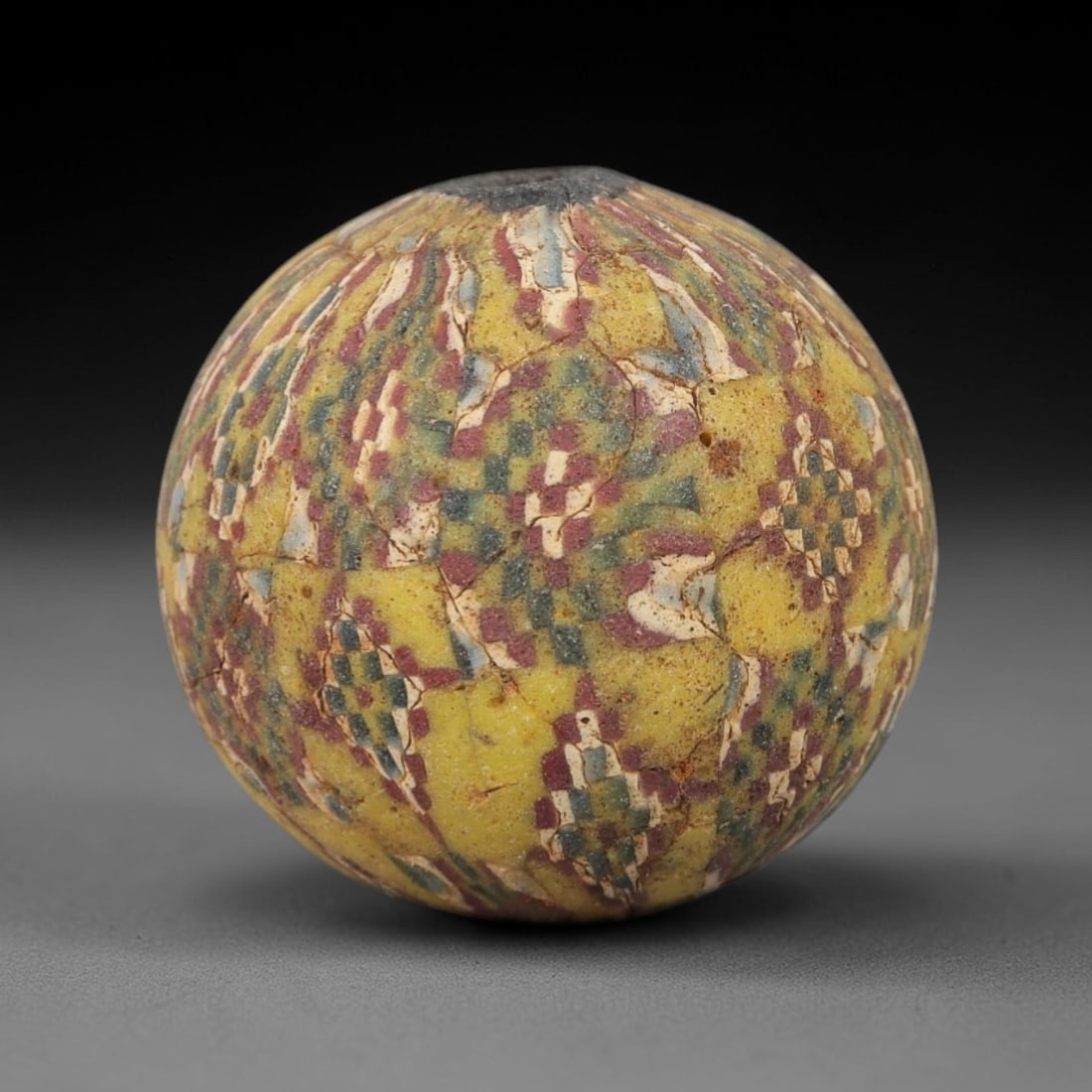 Ancient Glass Mosaic Bead - Roman Bead, 43ZM: This ancient bead is crafted from polychrome mosaic glass, formed using the millefiori technique characteristic of Roman glassworking traditions. The spherical form features a repeating geometric patt