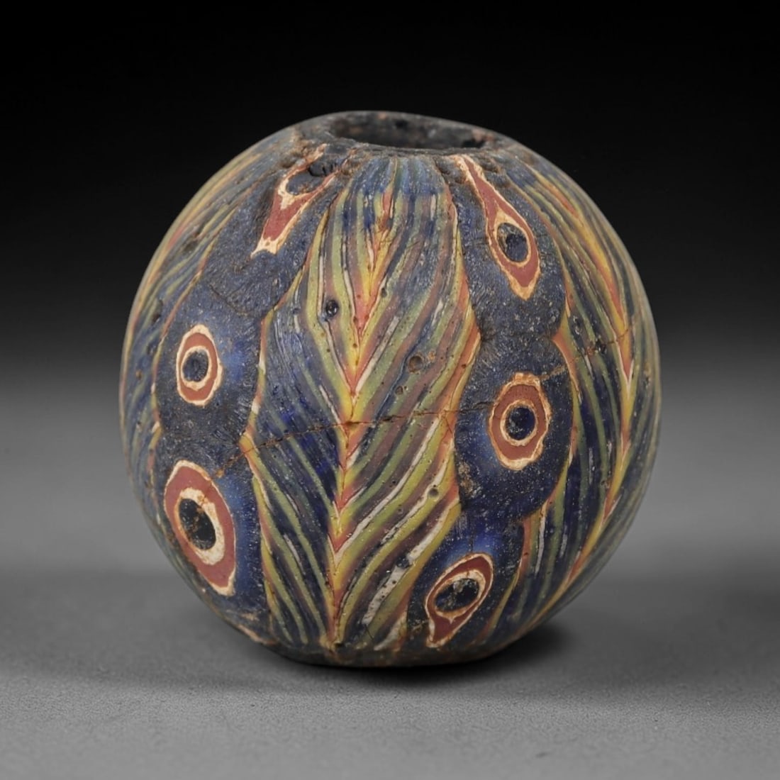 Ancient Glass Eye Bead - Egyptian Amulet Bead, 34ZM: This ancient bead is crafted from polychrome glass, formed using core-formed and trailed decorative techniques characteristic of Egyptian glassworking traditions. The spherical form features multiple