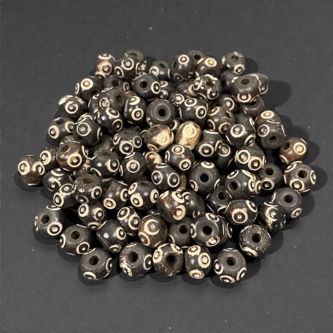 A Lot of Tibetan Bone Beads with Concentric Circle Motif, 20th Century, 99S: A substantial grouping of small, spherical bone beads, characteristic of Tibetan Buddhist devotional art. Each bead is uniformly sized and features the iconic concentric circle (dzi-eye) motif, render