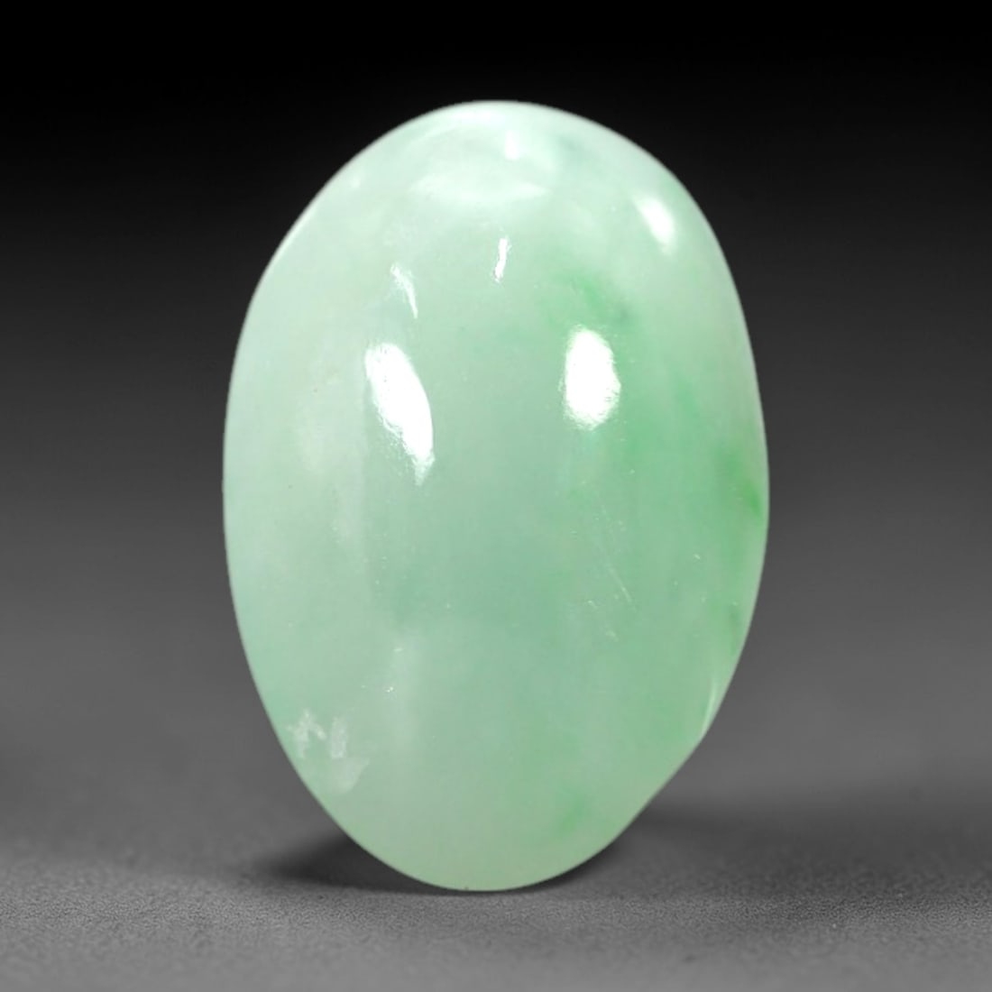 5.30 Carats Soft Green Translucent Jadeite Jade Cabochon - Natural Burmese Stonev, 39AB: This soft green jadeite jade cabochon features a smooth, oval form with a translucent, milky green hue that transitions to delicate, vibrant green patches across its polished surface. The stone's even