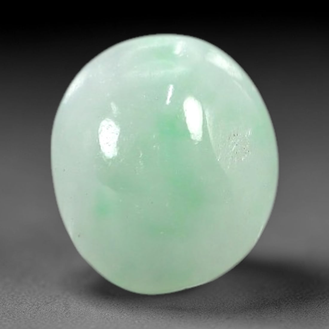 1.88 Carats Pale Apple Green Burmese Jadeite Jade Cabochon - Natural Loose Gemstone, 25AC: This oval Burmese jadeite jade cabochon exhibits a soft pale apple green hue, with delicate, concentrated patches of richer green that add subtle depth to its milky translucency. The smooth, polished