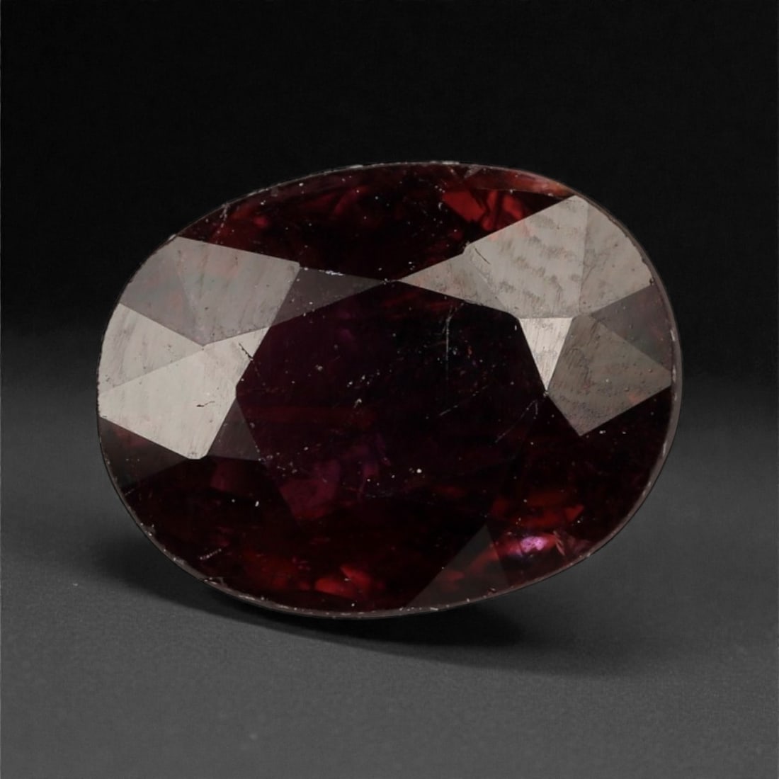 2.41 Carats Deep Red Garnet - Natural Mozambique - 9.7x7.5x4.4mm, 37WC: This bold oval-cut garnet glows with a velvety crimson tone, offering rich depth and an alluring play of burgundy and wine-red flashes. The gem's saturated body color and symmetrical faceting create a