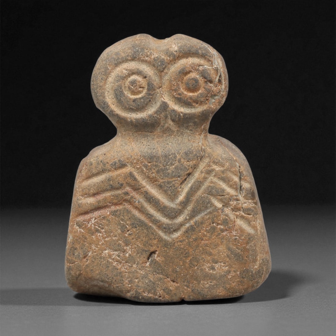 An Ancient Near Eastern Stone Eye Idol, 4th-3rd Millennium BCE, 45AC: Carved from a single piece of stone with a natural greyish-brown patina and fine mineral inclusions, the idol features a bulbous, bilobed head with two prominent concentric circular eyes, each defined