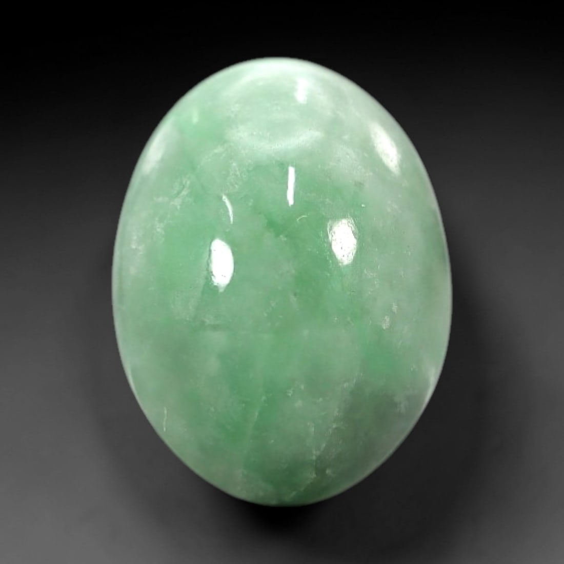 4.62 Carats Soft Green Translucent Jadeite Jade Cabochon - Natural Burmese Stone, 37AB: This soft green jadeite jade cabochon features a smooth, oval form with a translucent, milky green hue that transitions to delicate, vibrant green undertones across its polished surface. The stone's e