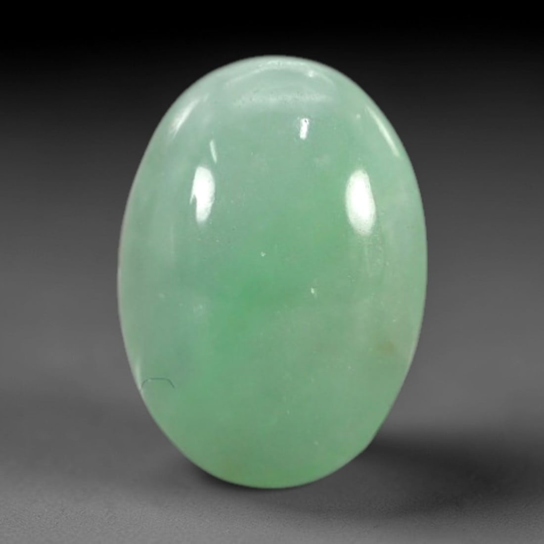 1.79 Carats Apple Green Burmese Jadeite Jade Cabochon - Natural Loose Gemstone, 48XN: This singular Burmese jadeite jade cabochon presents a luminous apple green hue, soft and luminous with a translucent quality that allows light to filter gently through its smooth, domed surface. The