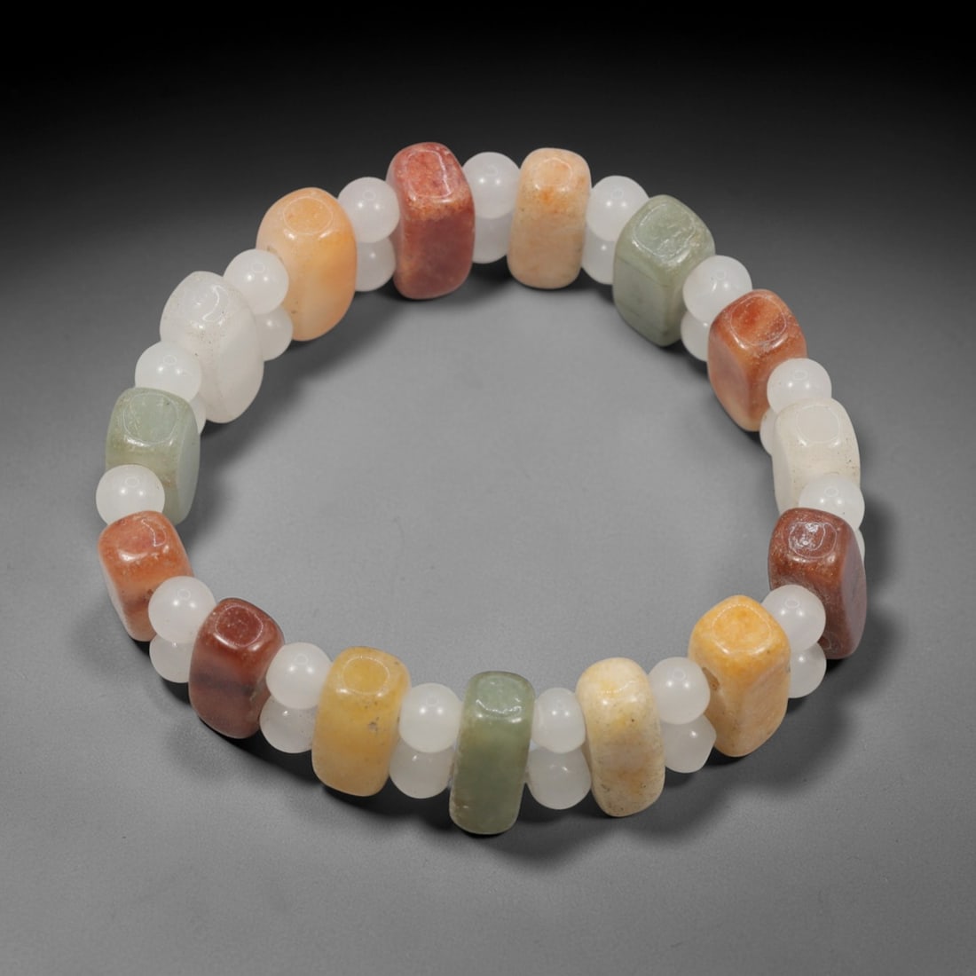 A Chinese Quartz and Jadeite Jade Bead Bracelet, 20th Century, 27ZK: Strung with barrel-shaped beads of quartz and jadeite jade, alternating with small spherical white quartz spacers. The barrel beads display a range of natural hues, including white, pale yellow, orang