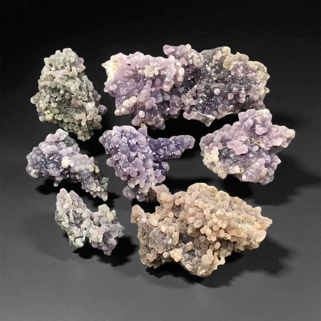 A Group of Grape Agate Specimens, 48EQ: Comprising seven specimens, each is formed from botryoidal chalcedony, exhibiting the characteristic "grape agate" morphology of densely clustered, rounded, translucent nodules. The specimens display