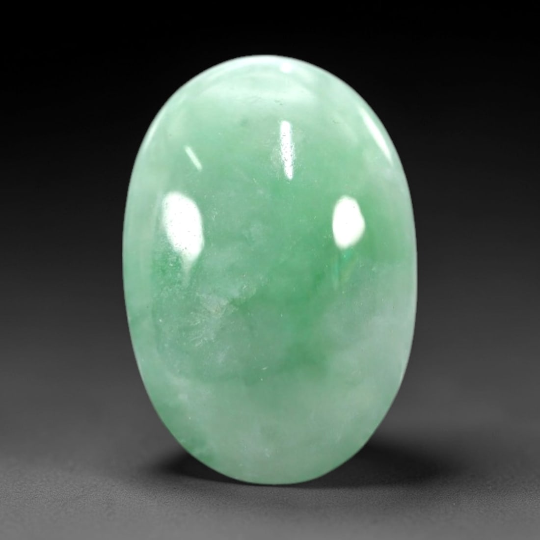 5.14 Carats Soft Green Translucent Jadeite Jade Cabochon - Natural Burmese Stone, 43AB: This soft green jadeite jade cabochon features a smooth, oval form with a translucent, milky green hue that transitions to delicate, vibrant green patches across its polished surface. The stone's even